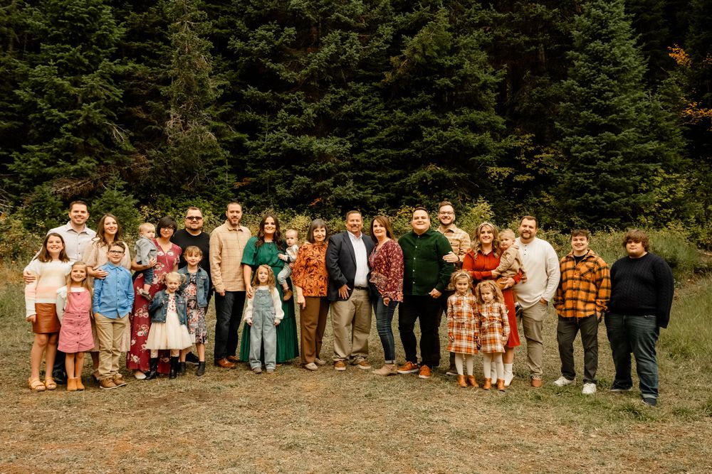 Panoramic group photo of wedding party lined up against forest background.