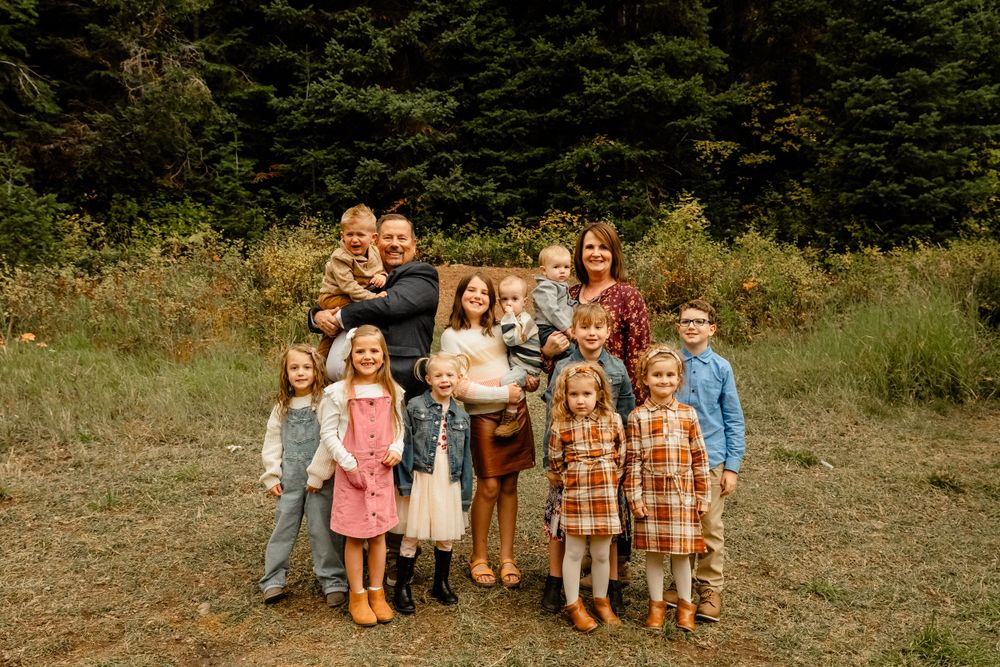 Extended family portrait with coordinated outfits against natural outdoor setting.