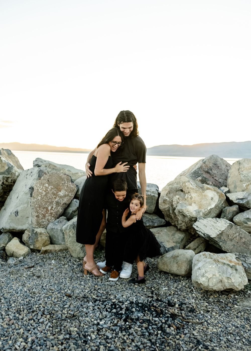 A tender family moment captured among rocky coastal scenery at sunset.