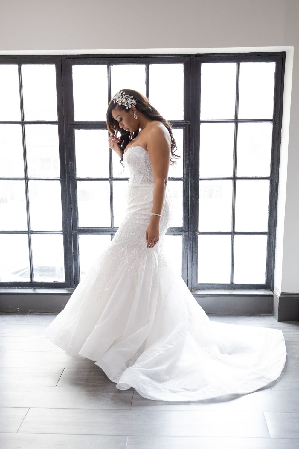 Elegant bridal portrait in front of window featuring dramatic mermaid gown with cathedral train.