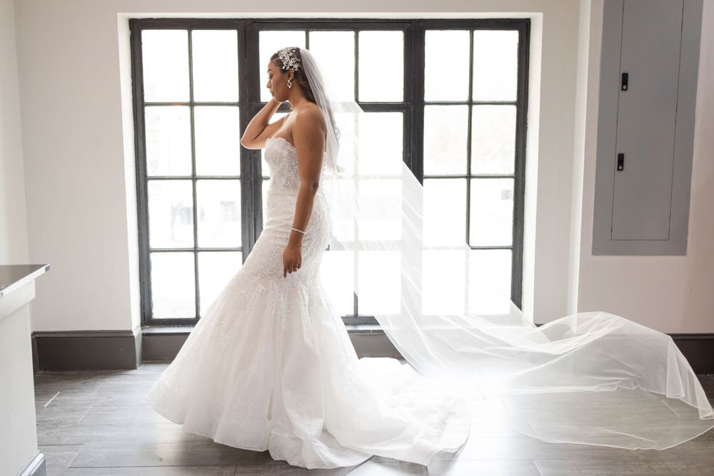 Ethereal bridal portrait with flowing veil and fitted mermaid silhouette.