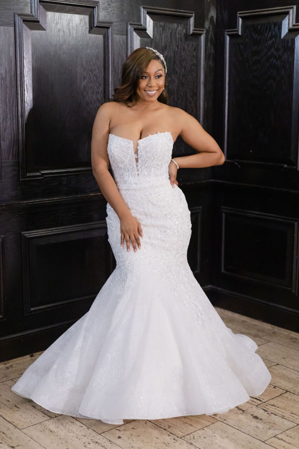 Stunning mermaid wedding gown with strapless sweetheart neckline and lace details against dark wood paneling.