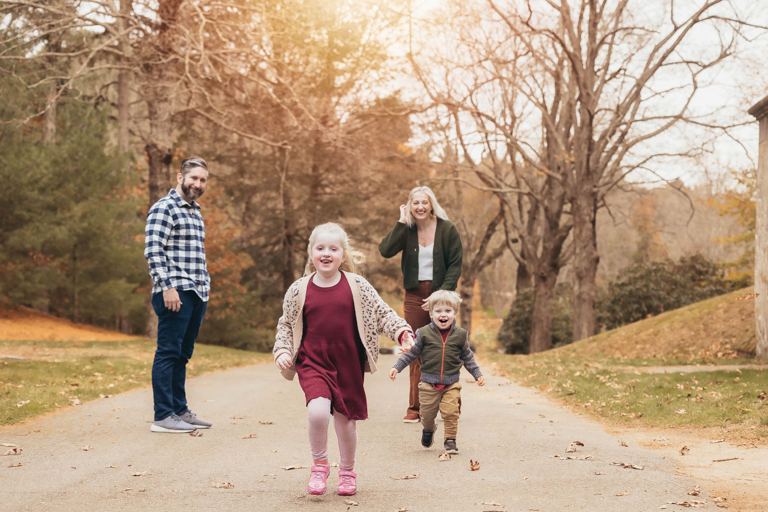 A family takes an autumn stroll together on a winding path through golden-leaved trees.