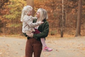 A tender moment shared between parent and child on an autumn afternoon in the woods.