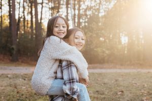 Two children hugging and laughing outdoors during golden hour.