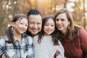 Family of four poses together for outdoor autumn portrait.