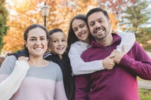 A family of four embraces while enjoying an autumn day outdoors.