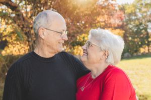 An elderly couple shares a loving moment in the autumn sunlight.