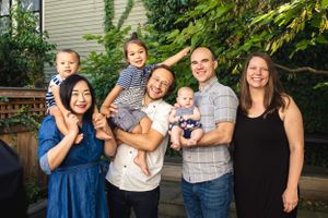 Family gathering outside home for group photo with children and adults.