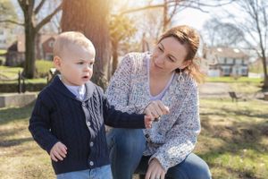 A parent and toddler share a playful moment in a sunny backyard.