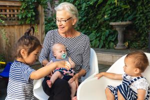 Multi-generational family moment outdoors with children on patio furniture.