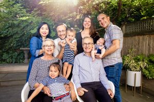 Multi-generational family poses together outdoors on a wooden deck during golden hour with natural backyard setting.