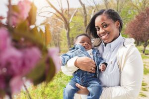 A mom and baby enjoy a spring day near blooming cherry blossoms.