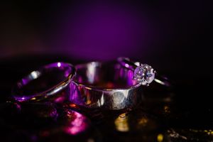 Wedding rings with diamond details captured in dramatic purple lighting.
