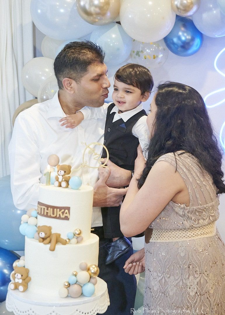 first birthday parents with son behind cake