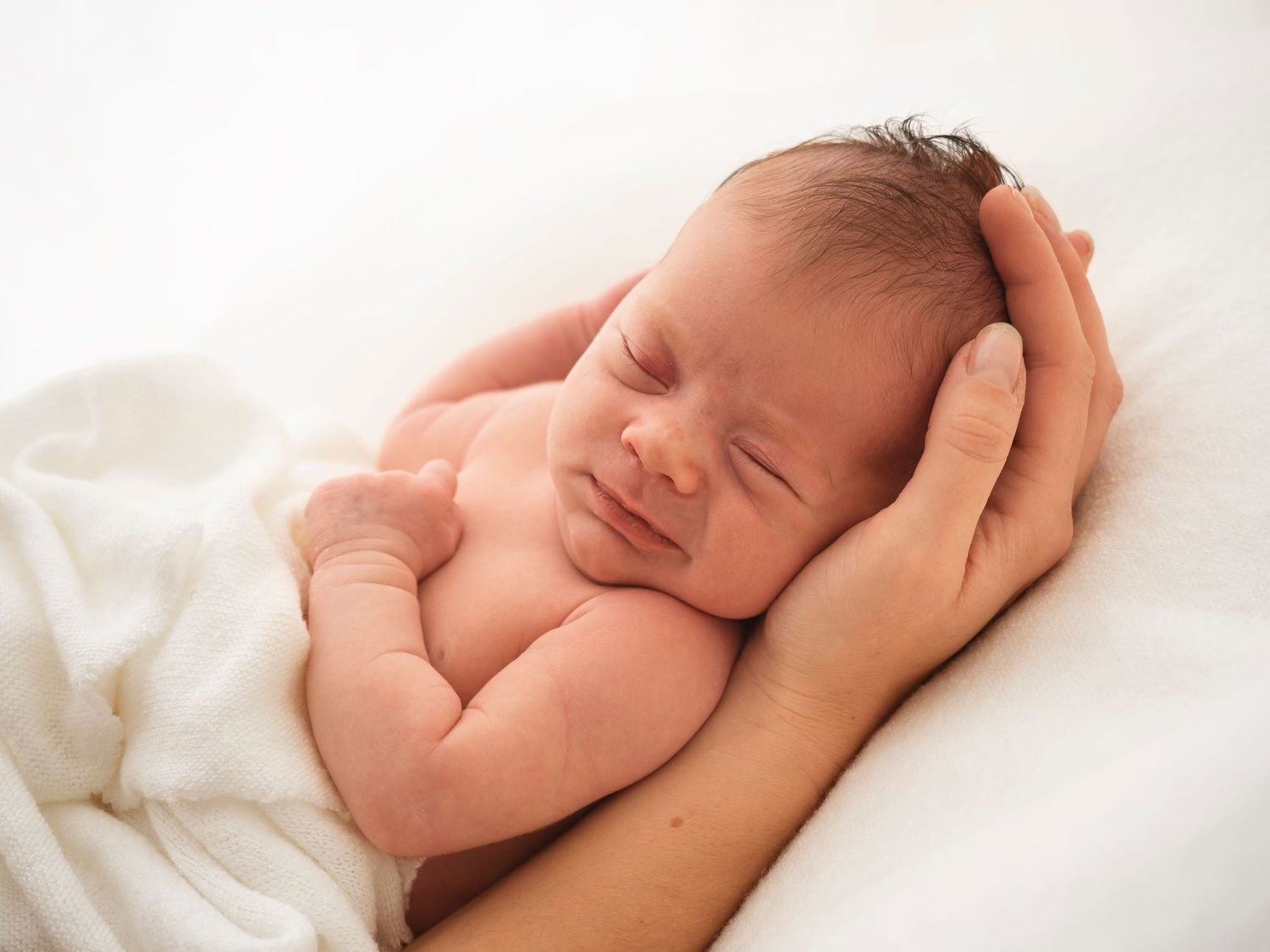 newborn baby held in mothers hands lays sleeping during a photoshoot