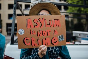 protester holds up Asylum is not a crime sign at protest portland oregon photojournalism