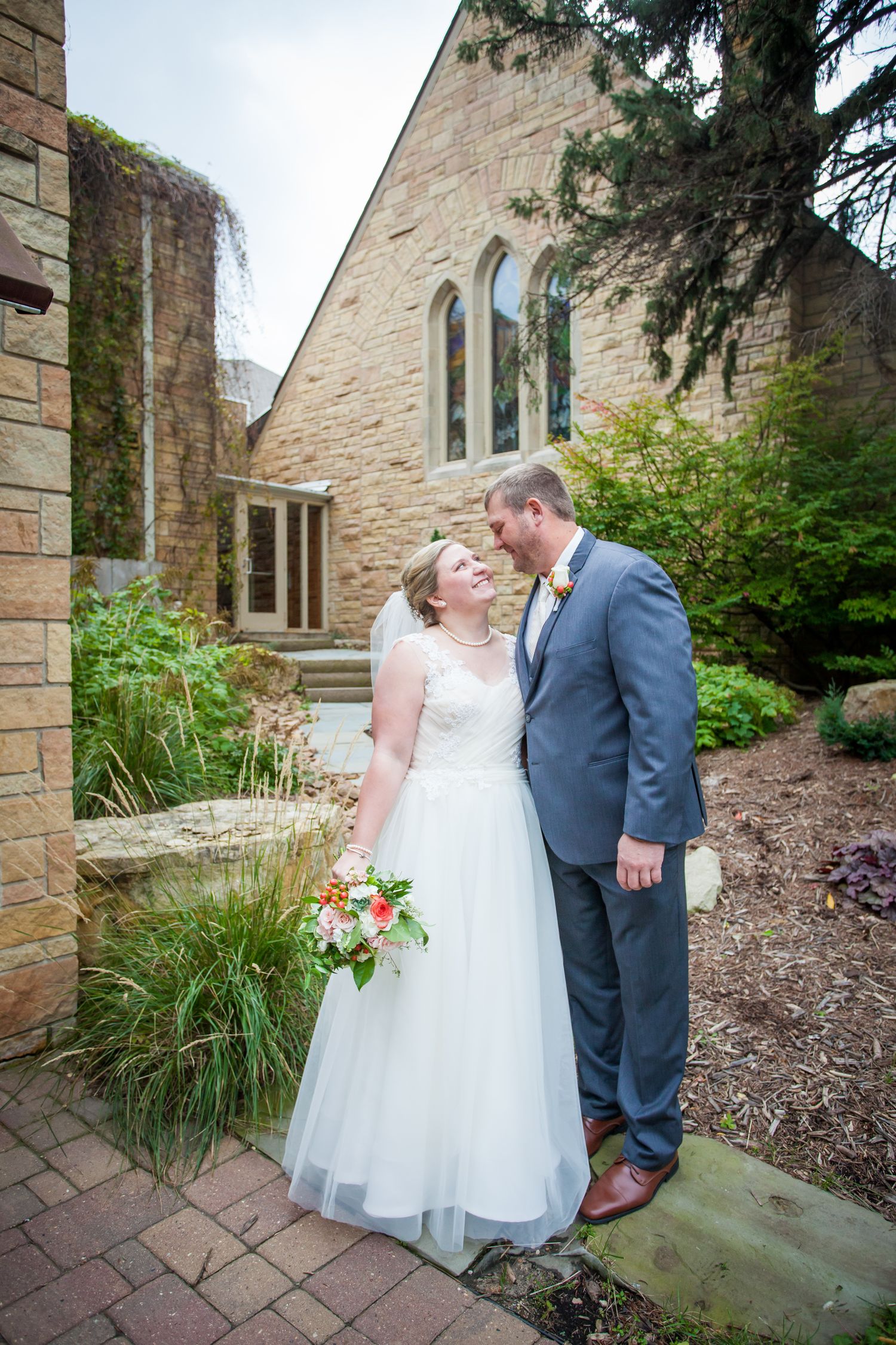 A couple shares intimate moments outside a stone church building during their wedding day.