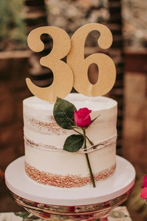 White birthday cake with number 30 topper and pink rose decoration.