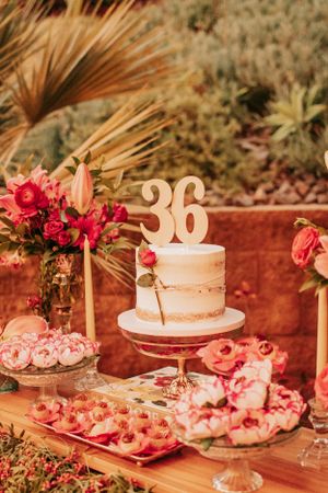 Desert table with pink theme featuring 30th birthday cake and floral decorations.