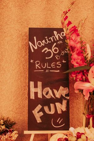 Chalkboard signs with fun text and pink flowers displayed at a celebration event.