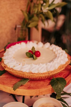 A cream pie topped with whipped cream and garnished with berries and leaves.