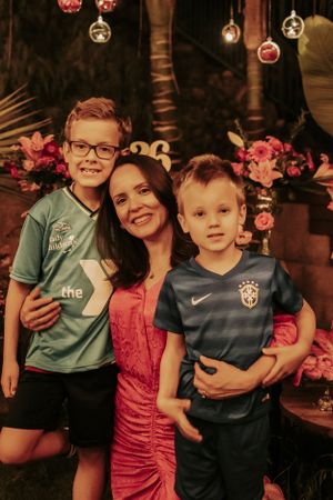 Family portrait with athletic jerseys against a backdrop of hanging ornaments and tropical foliage.