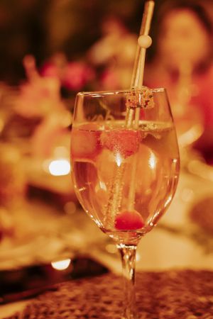 Close-up of a champagne glass with raspberry garnish in warm ambient lighting.