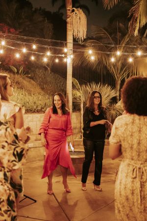 Evening outdoor gathering with string lights and palm trees creating a warm ambiance.