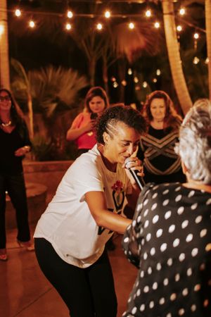 Energetic dancing scene at night under string lights and tropical decor.