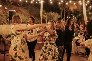 People dancing joyfully under twinkling lights at a tropical outdoor celebration.