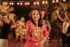 Woman in pink holding champagne glass while dancing at outdoor celebration.