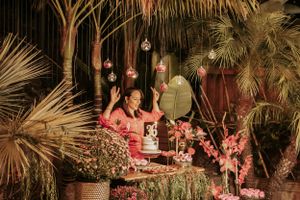 Tropical party decor with hanging glass orbs and palm fronds under evening lighting.