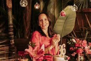 Party celebration setup with pink flowers, hanging lights and tropical greenery.