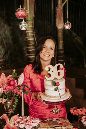 A 36th birthday party setup with pink decor, roses and a white cake displayed in an outdoor evening setting.