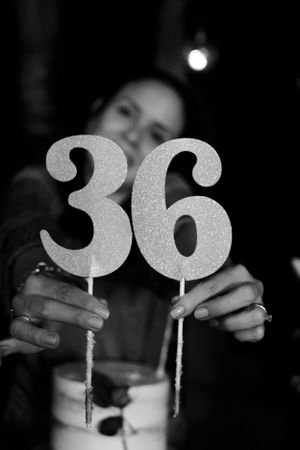 A close-up black and white photo of glittery number 36 cake toppers on sticks.