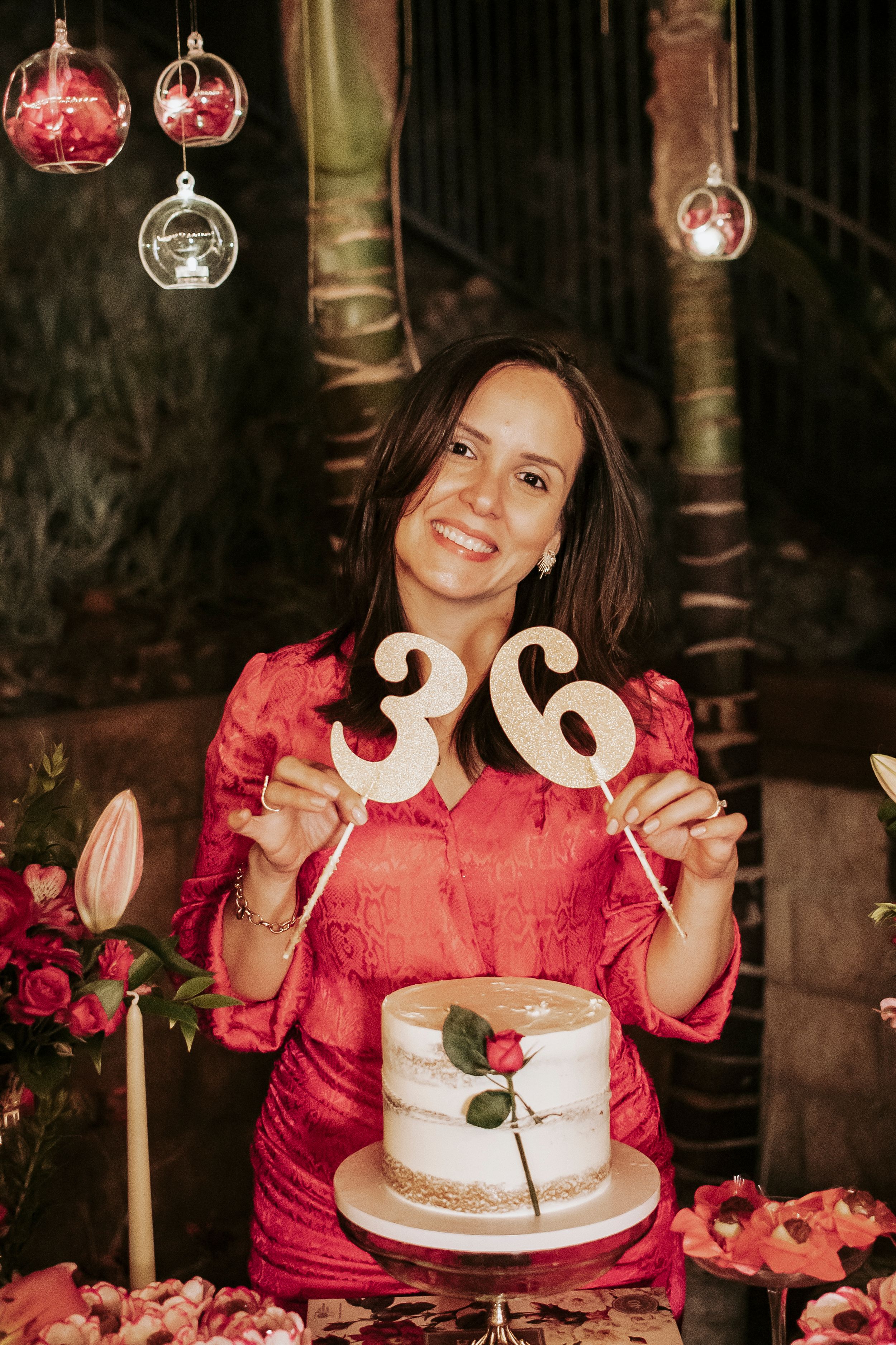 A festive birthday setup featuring a white cake with number 36 toppers and hanging glass ornaments.
