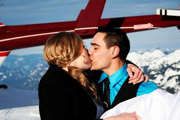 A romantic kiss against a snowy mountain backdrop with a red plane visible in the background.