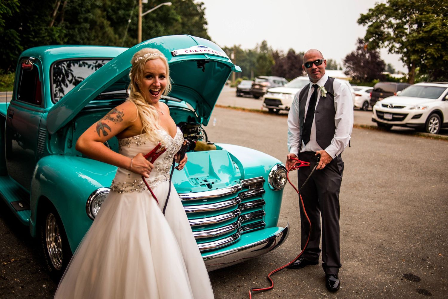 Couple poses with a vintage turquoise Chevrolet pickup truck on their wedding day.
