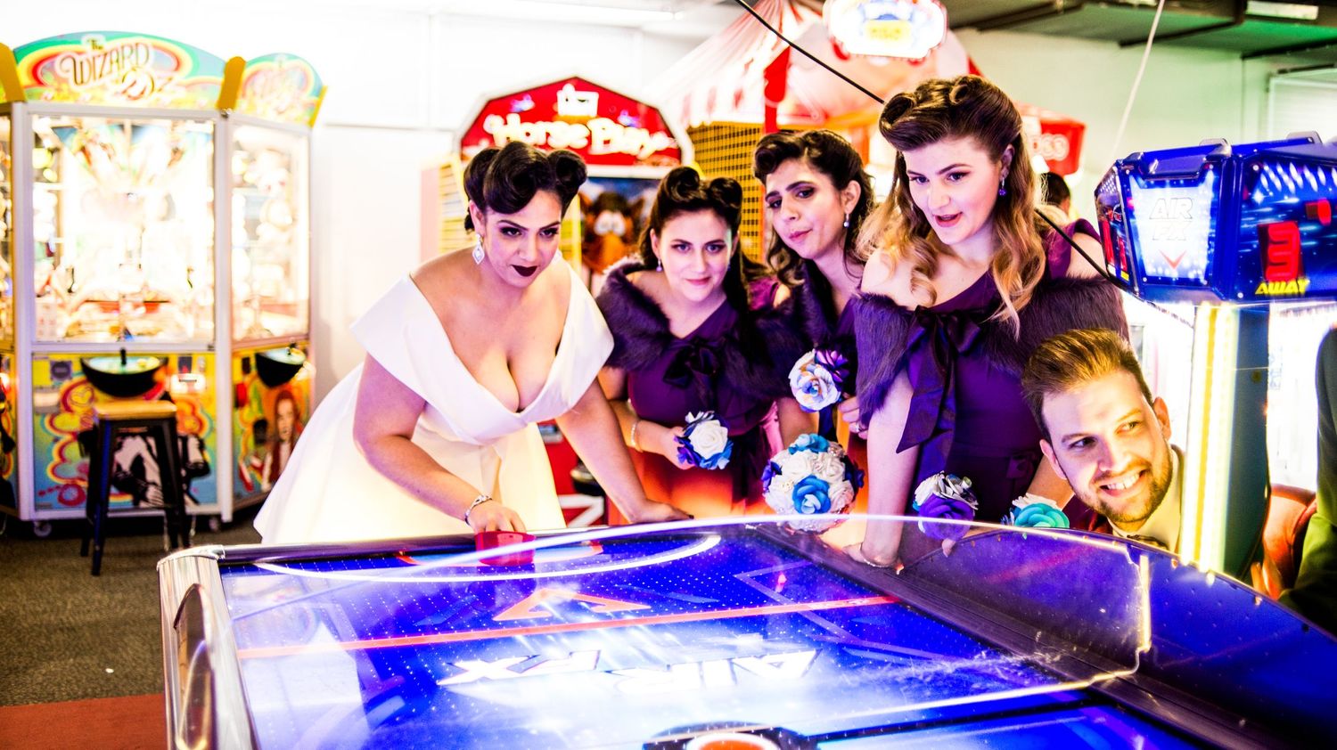 Group plays arcade games together with neon lighting creating a vibrant atmosphere.