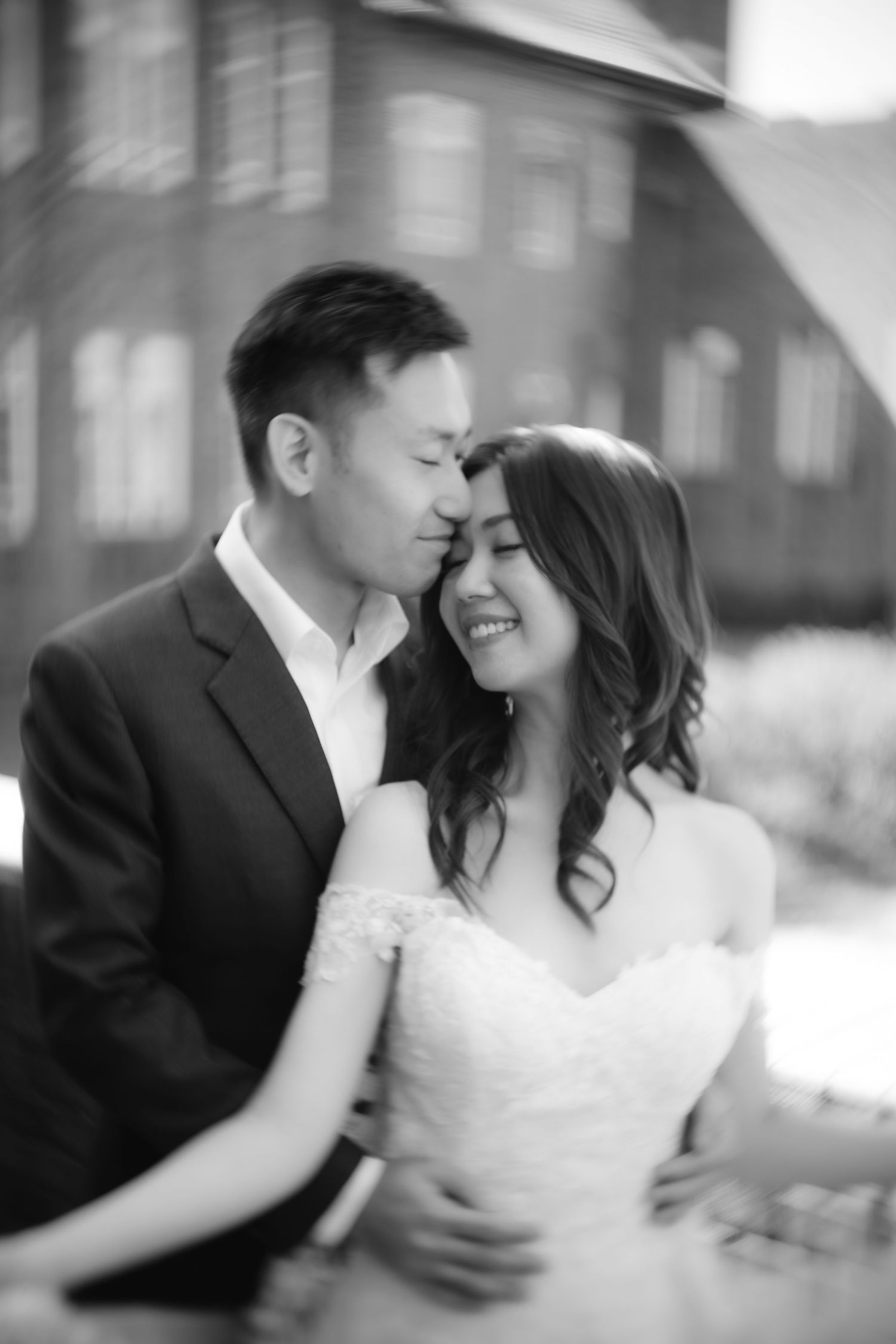 A romantic black and white portrait of a wedding couple sharing an intimate moment.