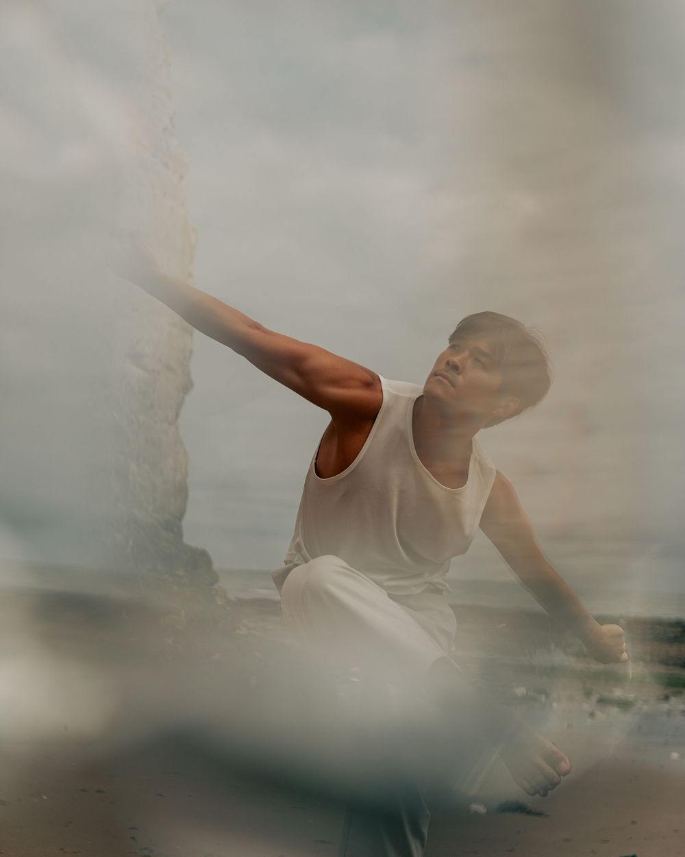 A dancer in white strikes a graceful pose against a soft, dreamy background.