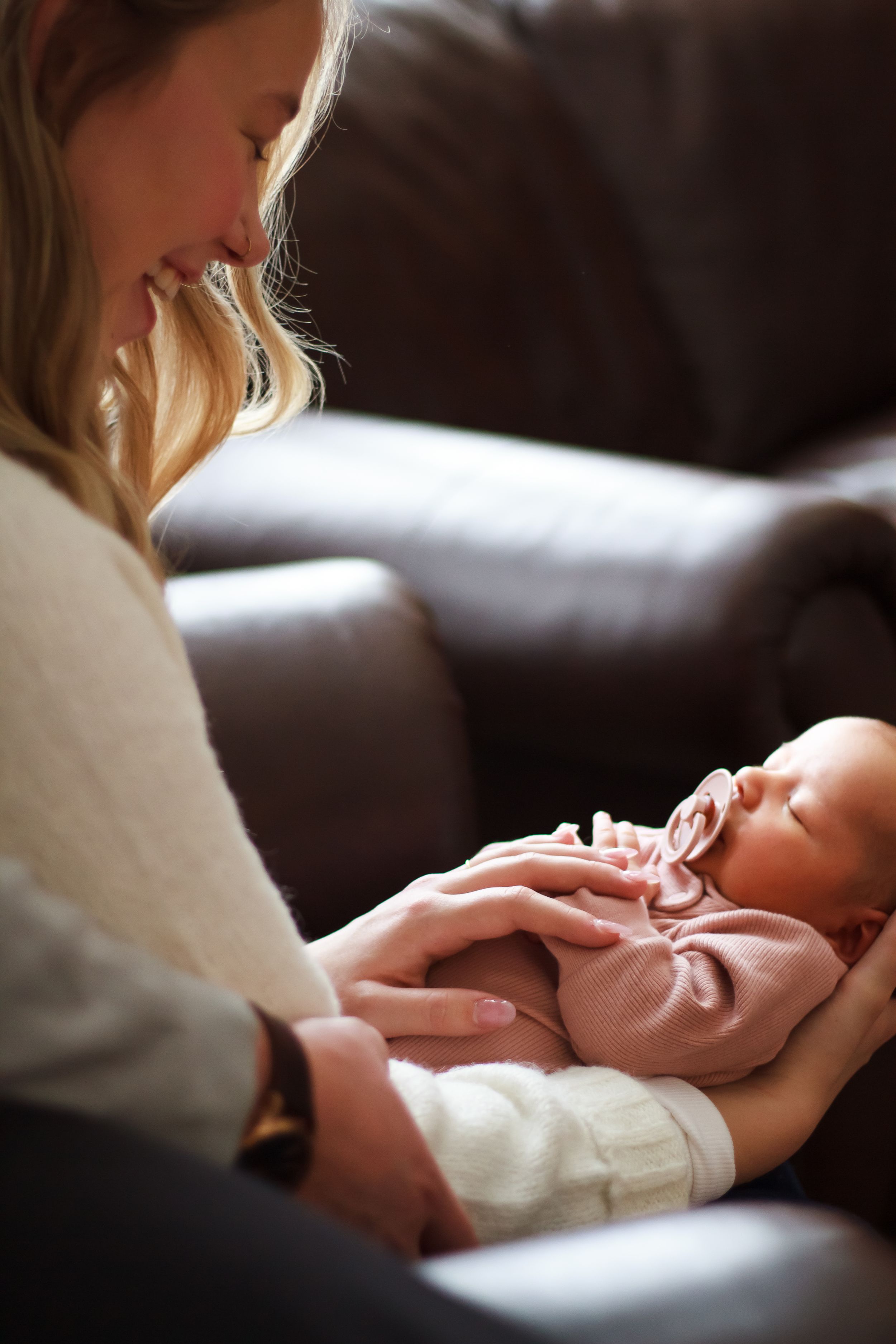 Mom laughing holding baby during lifestyle newborn session.
