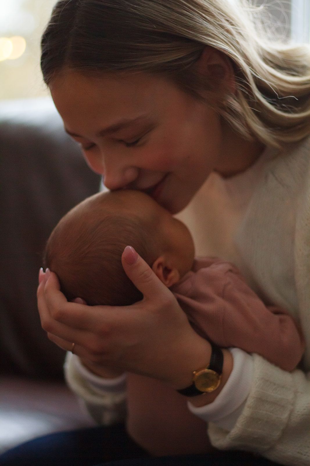 Close up of mom kissing newborn on the forhead during lifestyle newborn session.