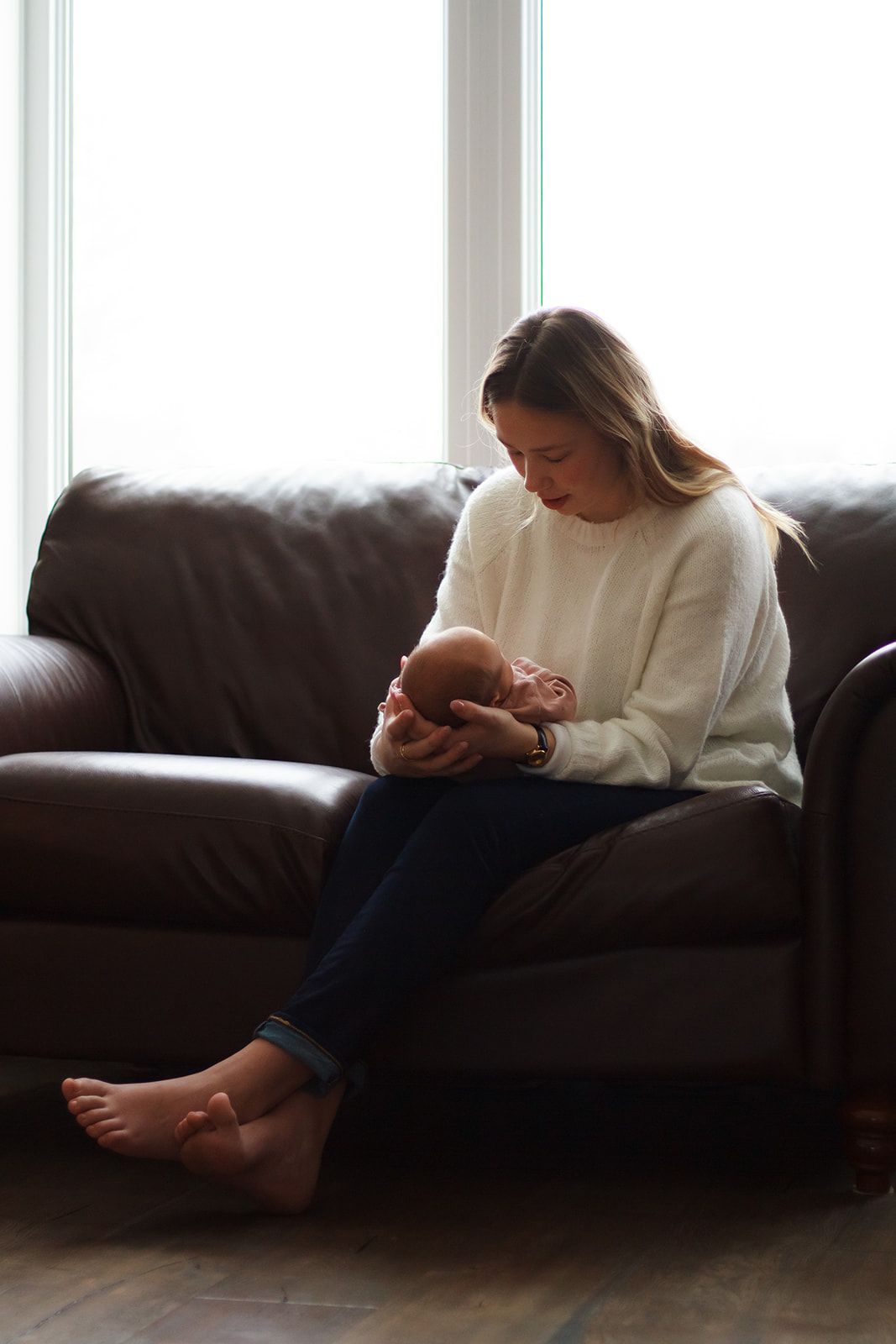 Far away of mom holding baby during lifestyle newborn shoot.