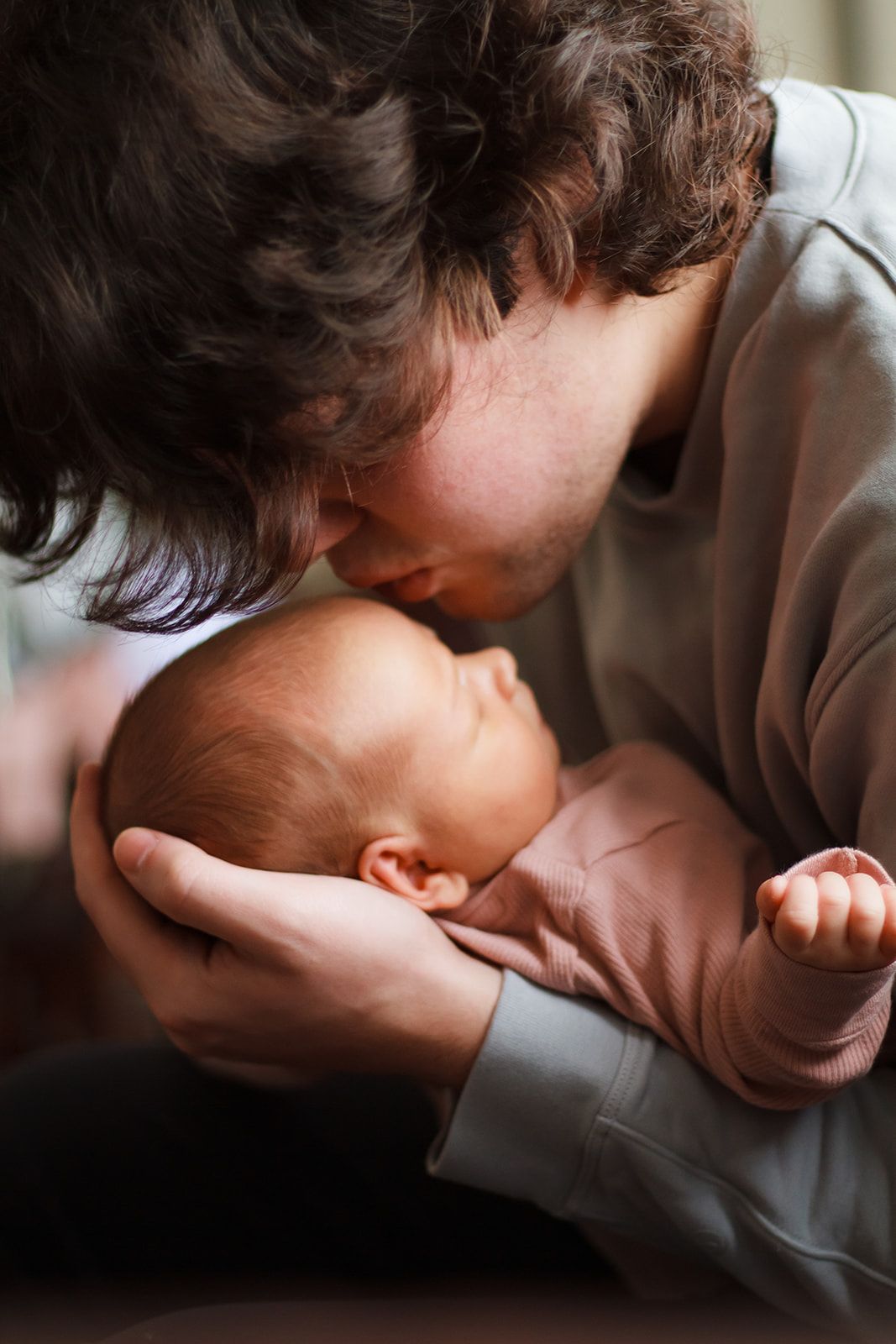 Dad kissing newborn baby on the forhead during lifestyle newborn session.