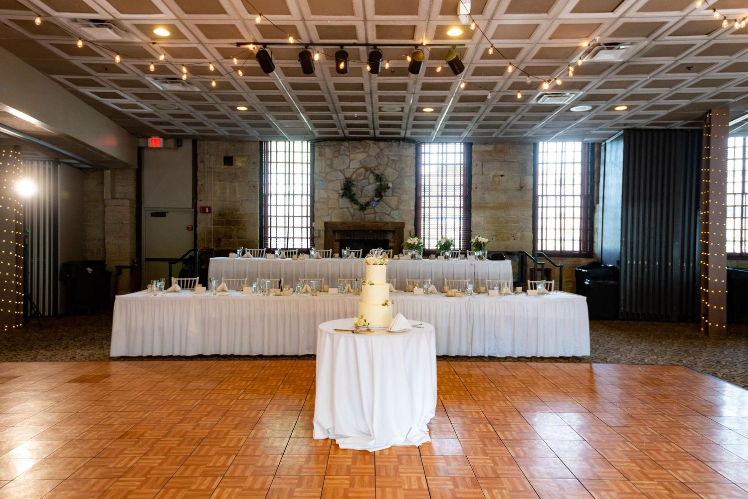 Spacious reception hall with coffered ceiling and hardwood floors ready for event setup.