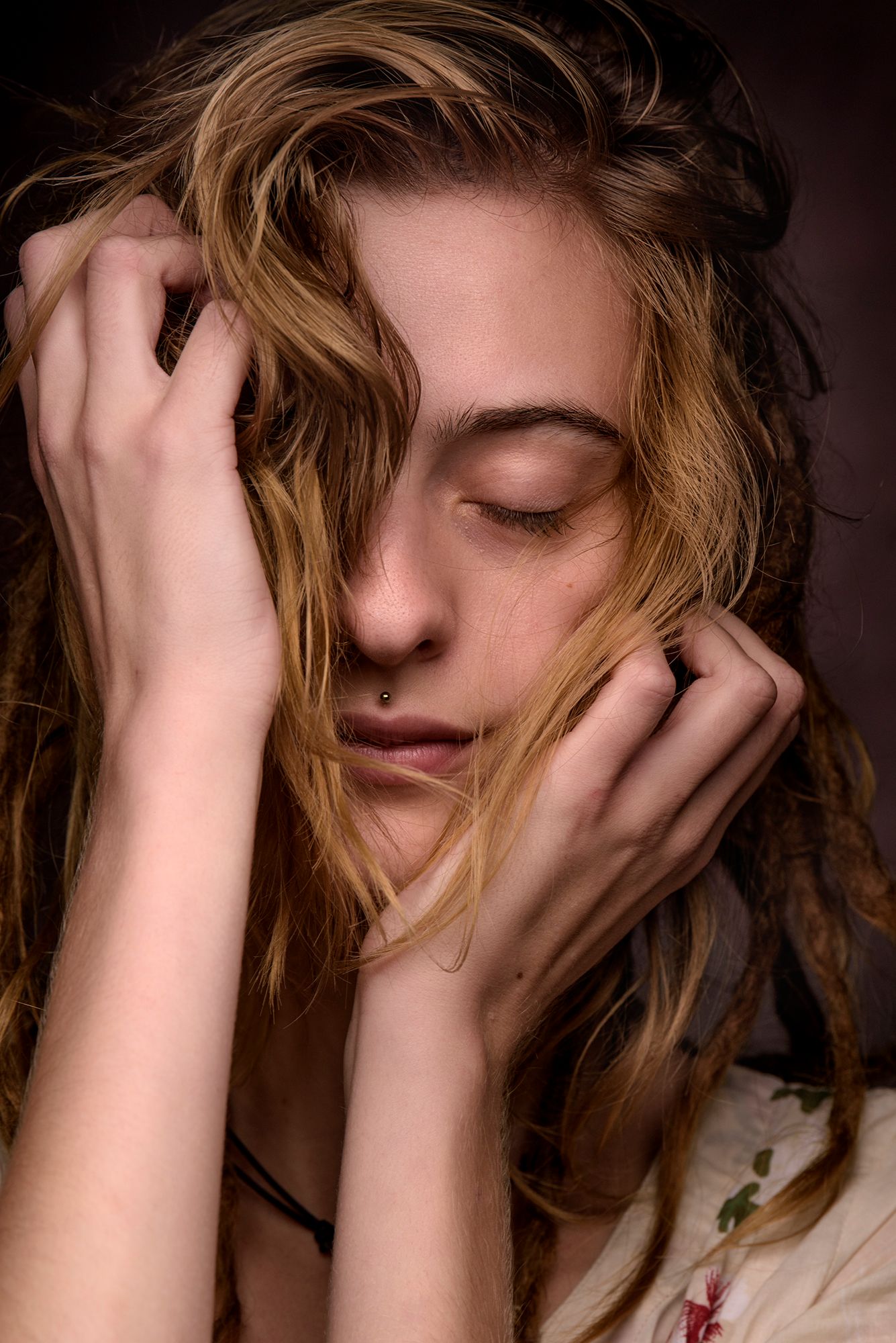artistiek portret van een jongedame met gesloten ogen en de handen in het haar