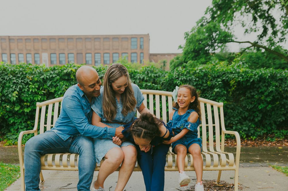 A family shares a relaxed moment together on a wooden park bench.