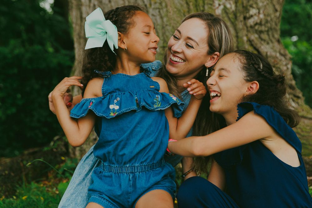 A candid moment of laughter and embrace captured outdoors against a natural backdrop.
